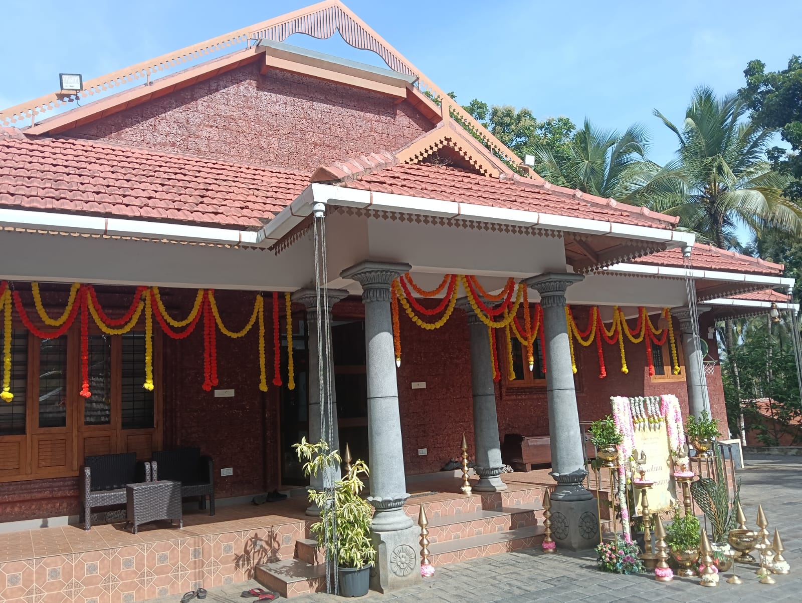 The house in daylight, pillars draped with marigold garlands