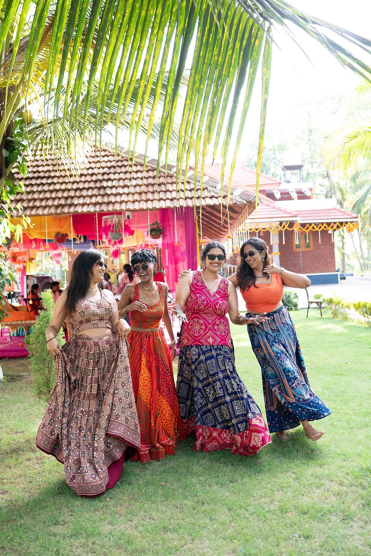 Friends in bandhani lehengas dancing on the lawn during a mehendi celebration