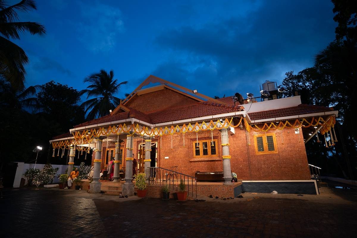 The Kalapura house at twilight, pillars draped with marigold garlands