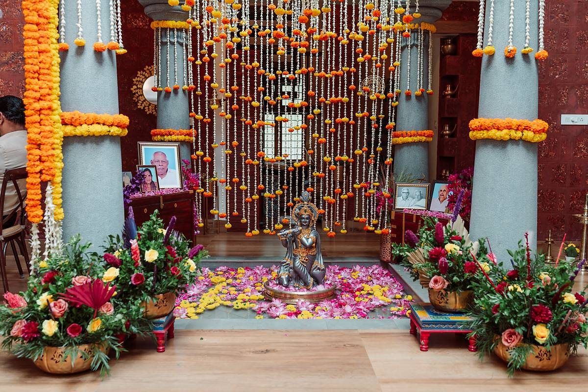 Krishna idol shrine framed by cascading marigold garlands and flowers