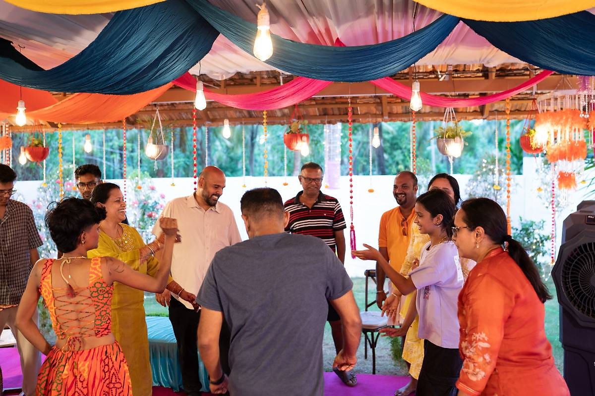 Guests dancing under the colourful draped mandap ceiling